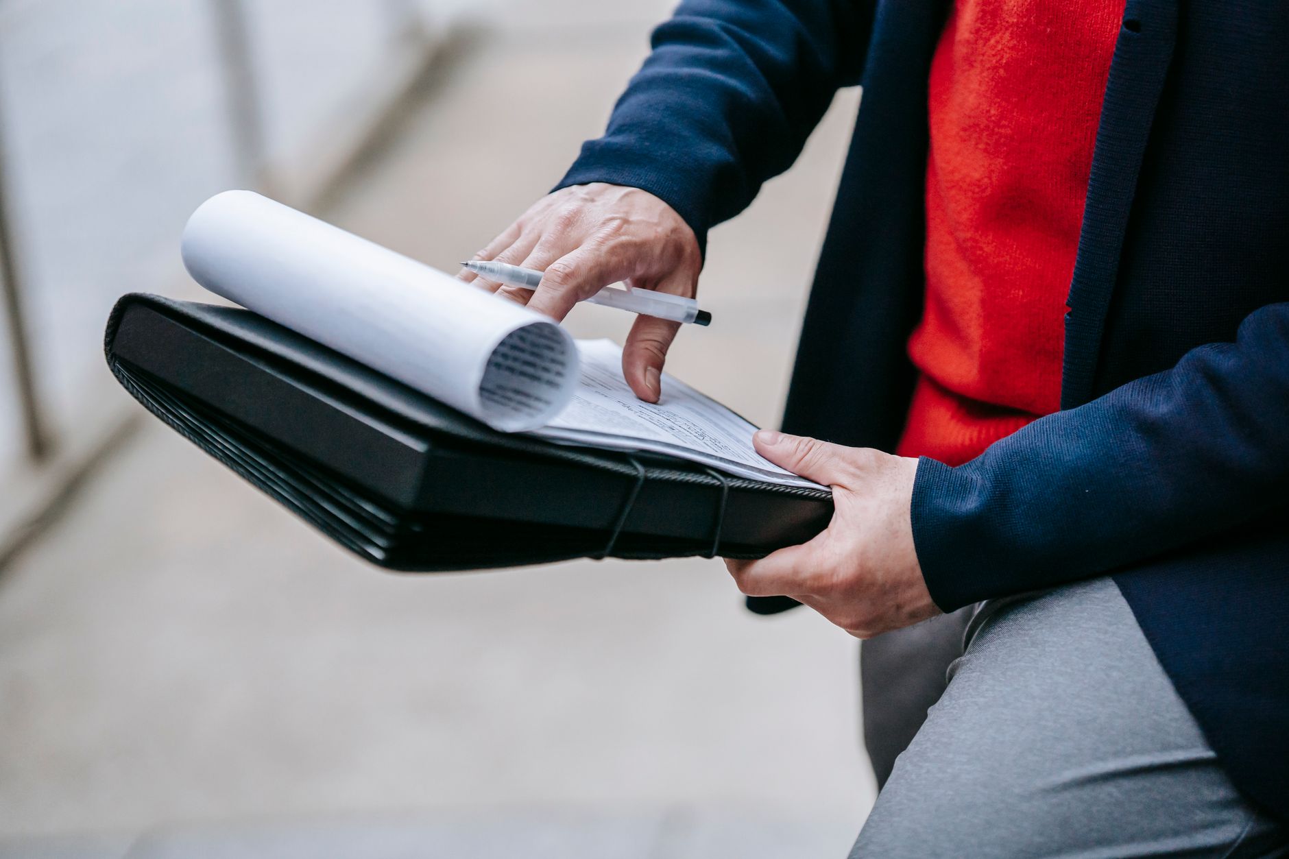 Close-up of a professional person reviewing documents outdoors. Engaged in work with focus on writing materials. — eladelanta