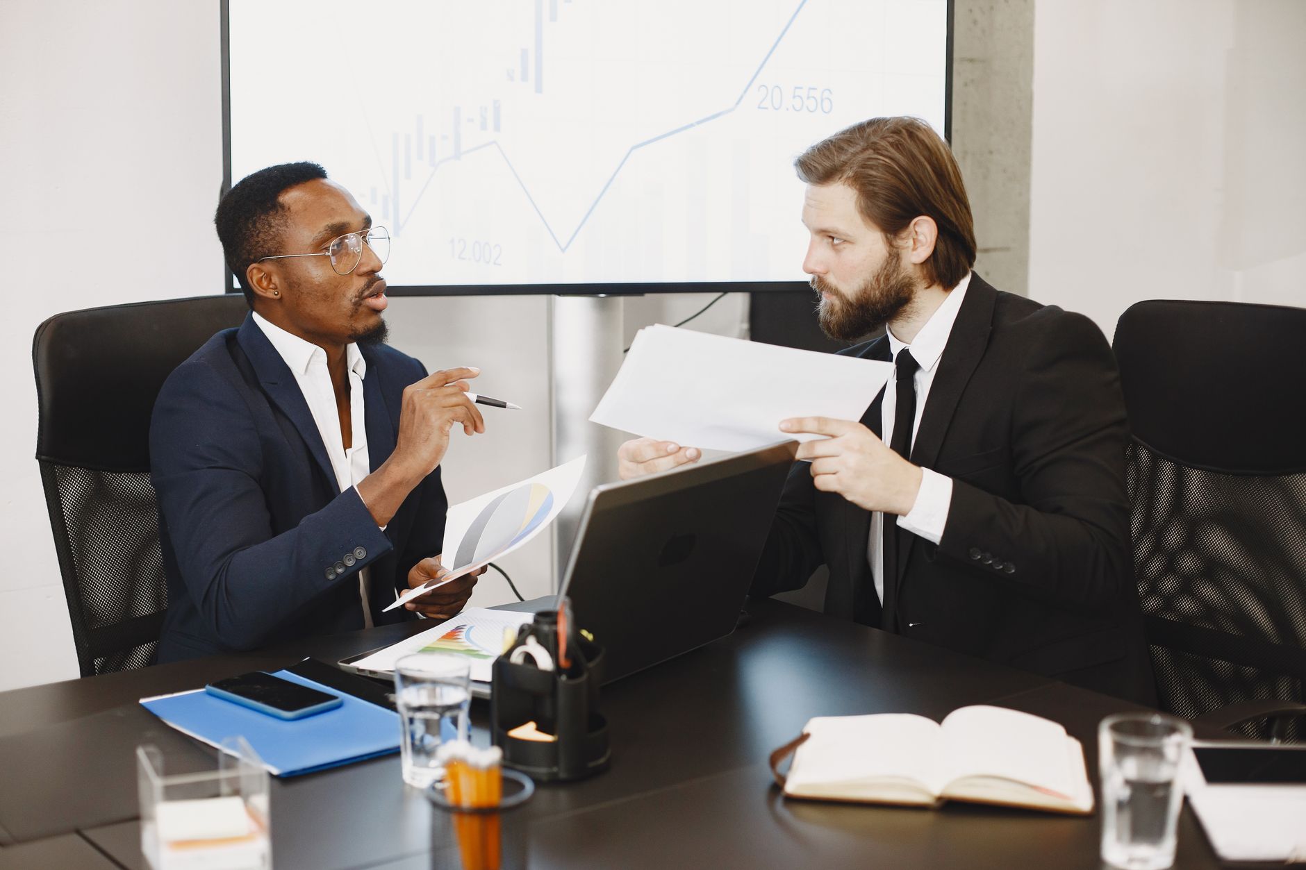 Two business professionals engaged in a planning meeting, discussing documents in a modern office setting. — Exploring IP TV