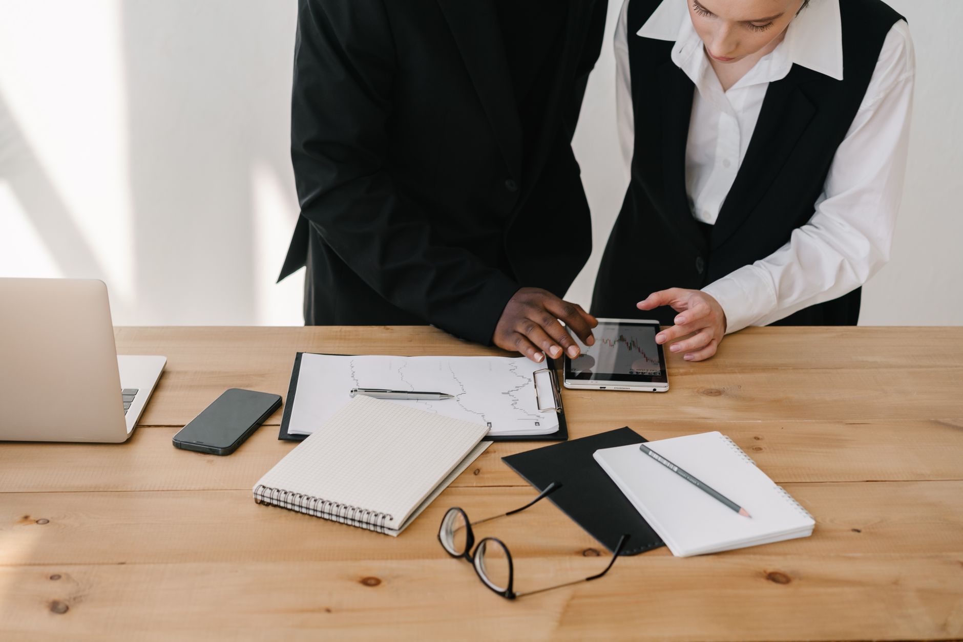 Two professionals collaborating over charts and tablet in a modern office setting. — Tools and Strategies Commonly Used by Fo